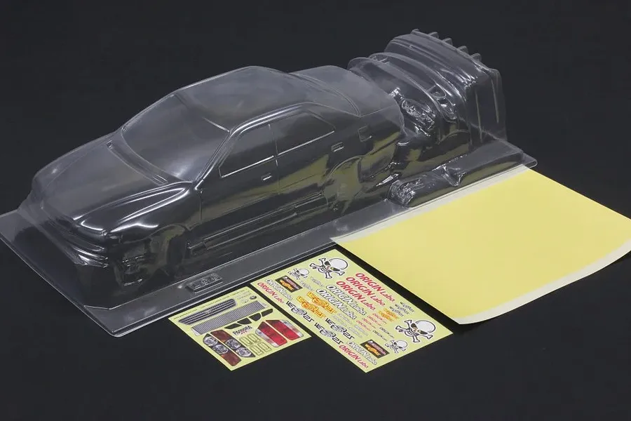 Clear unpainted polycarbonate RC car body shell with separate decal sheets and mask sheet on a dark background.