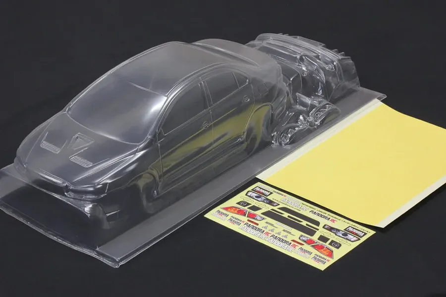 Pandora RC unpainted clear 1/10 Mitsubishi Lancer Evolution X body shell with decal sheet and window masks on black background.