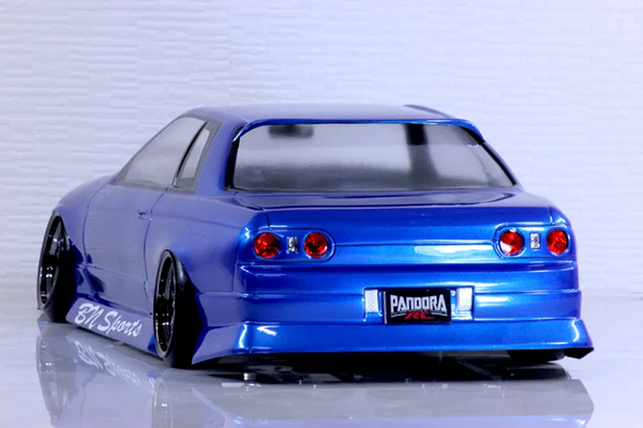 Rear three-quarter view of a metallic blue Pandora RC HCR32 2Dr BN Sports drift car body shell on a reflective surface.