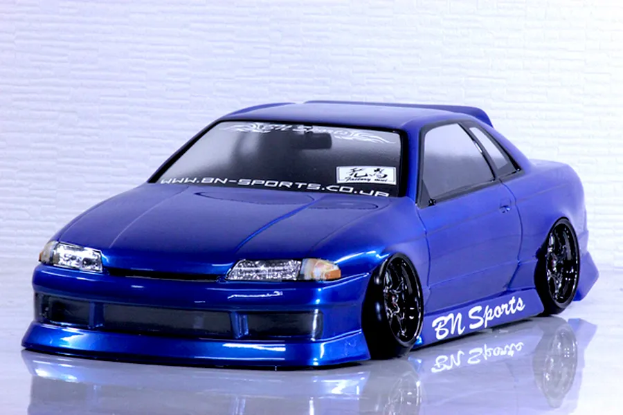 Blue painted RC drift car body shell mounted on a chassis with custom wheels and BN Sports decals.