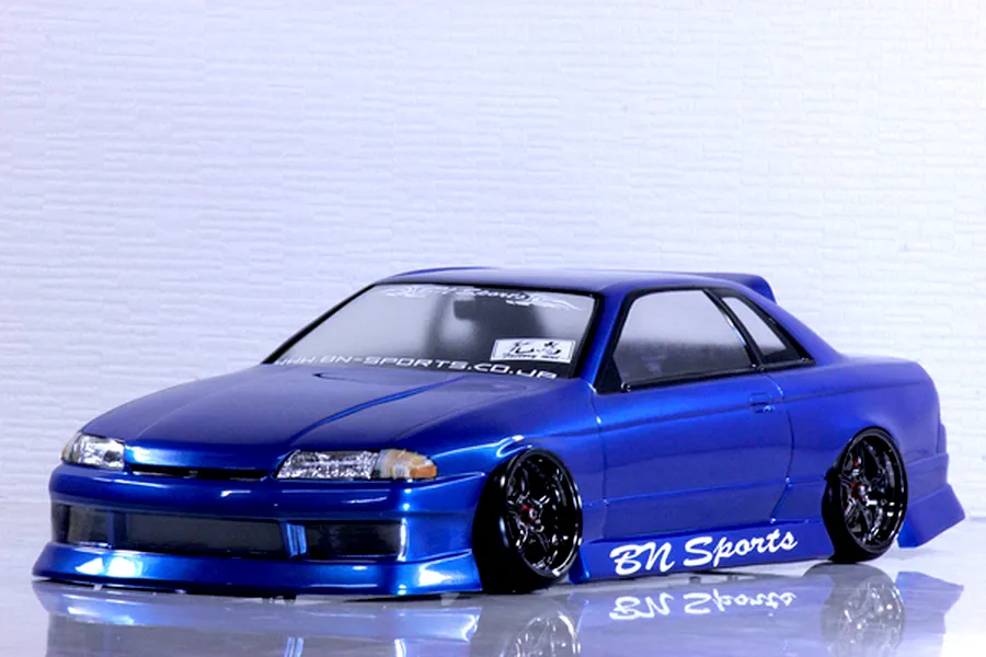 A painted blue Pandora RC HCR32 2Dr BN Sports drift RC car body mounted on a chassis with custom wheels against a white textured background.