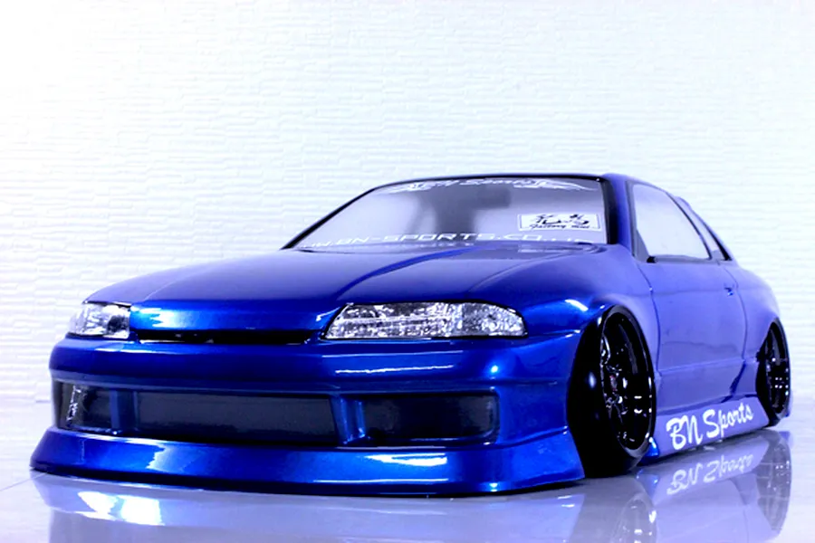 Front three-quarter view of a metallic blue RC drift car body shell styled after an R32 Nissan Skyline with BN Sports aero kit.