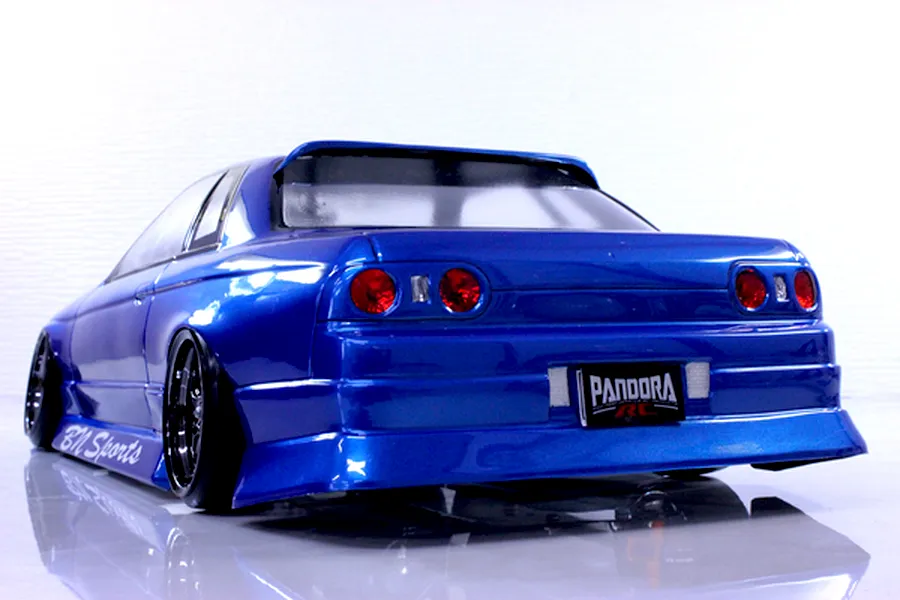 Rear three-quarter view of a blue Pandora RC HCR32 2Dr BN Sports body shell on a drift car with custom wheels against a white background.