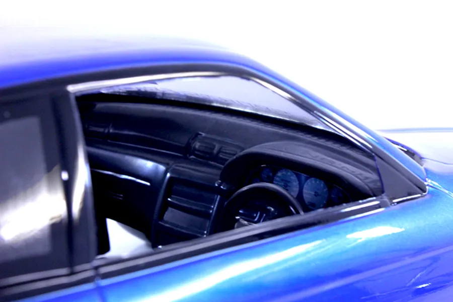 Close-up interior view of a blue RC car body showing the dashboard, steering wheel, and gauges through the side window.