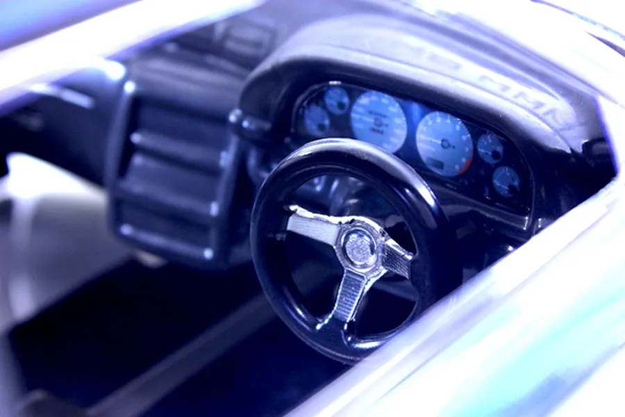 Close-up of a detailed RC car cockpit interior showing a steering wheel, dashboard, and instrument cluster.