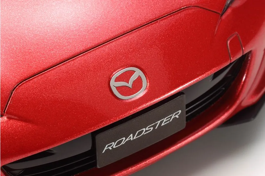 Close-up of the front bumper of a red Tamiya 1/24 scale Mazda Roadster model car, featuring the Mazda emblem and a license plate reading ROADSTER.