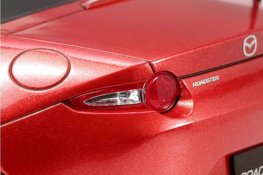 Close-up of the rear taillight and trunk area of a red Mazda MX-5 model car, showing the metallic paint finish and Mazda branding.