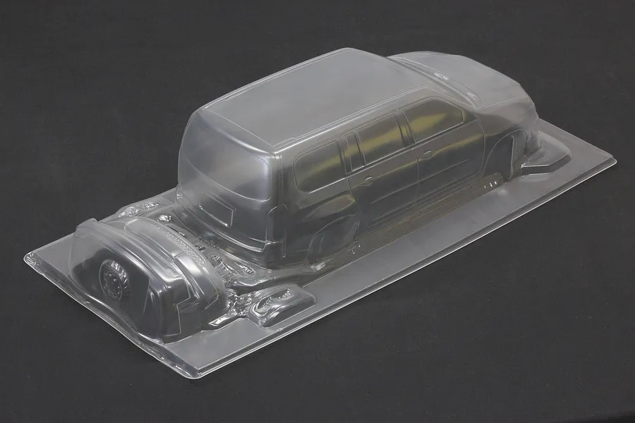 Uncut and unpainted clear polycarbonate RC car body shell for a Toyota Probox on a dark surface.