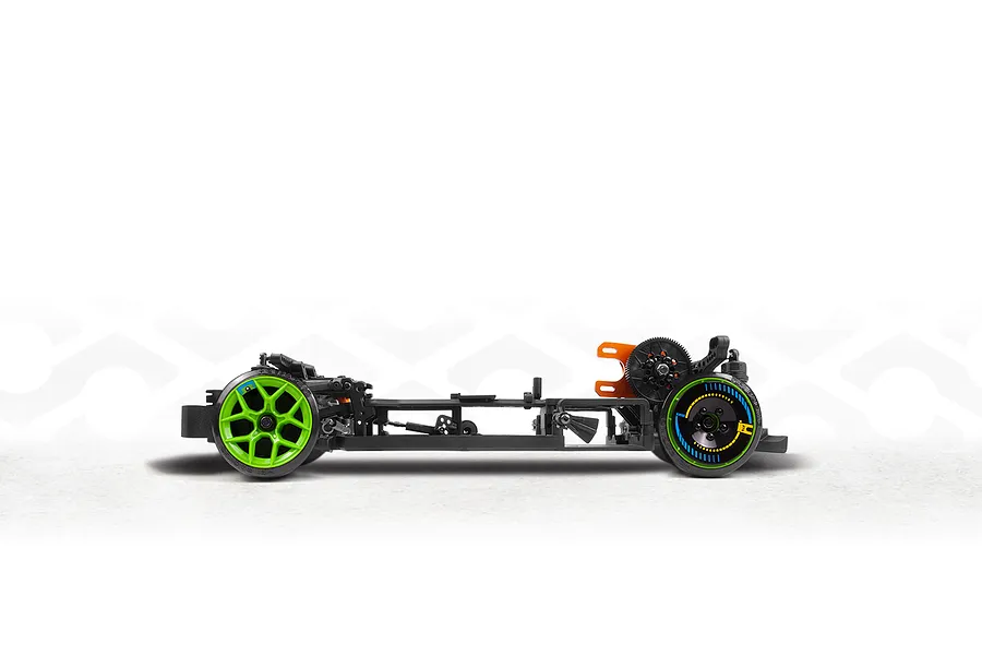 Side view of an RC drift car chassis featuring black components, bright green wheels, and an orange motor mount on a white studio background.