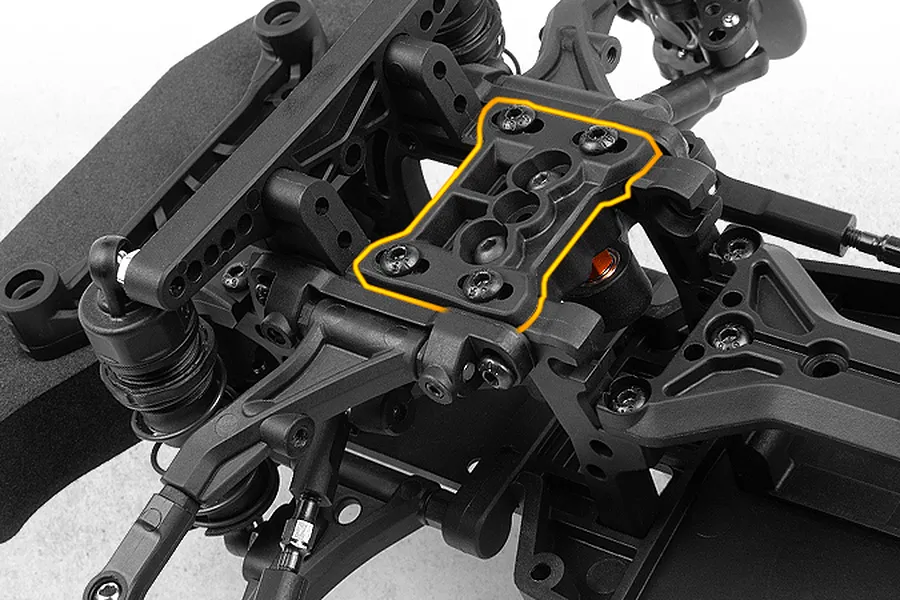 Close-up studio shot of an RC car chassis highlighting a specific black plastic top deck component with an orange outline.