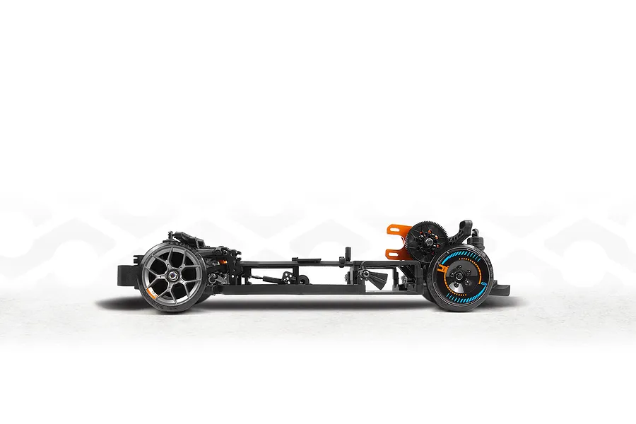 Side view of an assembled RC drift car chassis showing black frame, suspension components, and wheels against a white background.