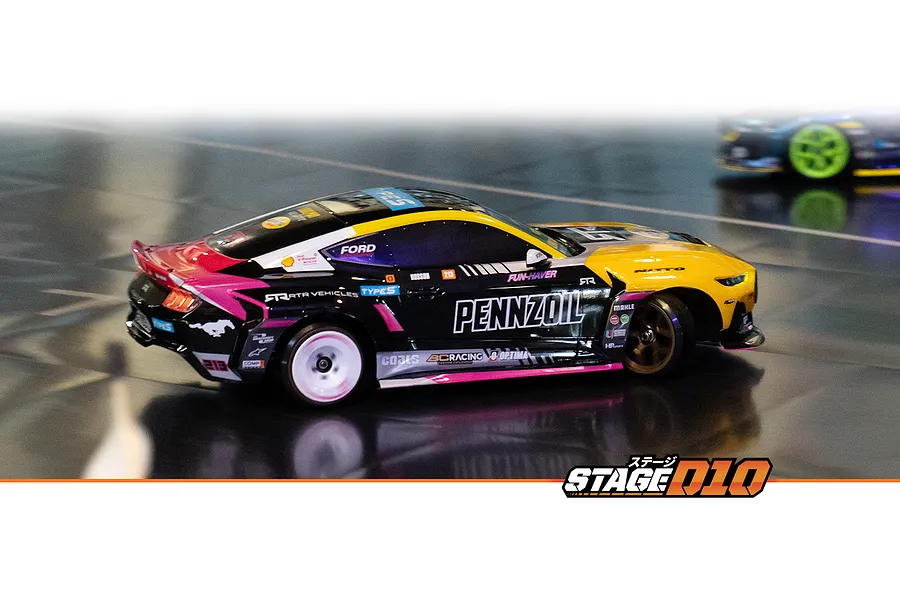 HPI Stage-D10 Ford Mustang GT Spec-5 RC drift car in action on a smooth track, featuring a custom black, yellow, and pink livery with Pennzoil branding.