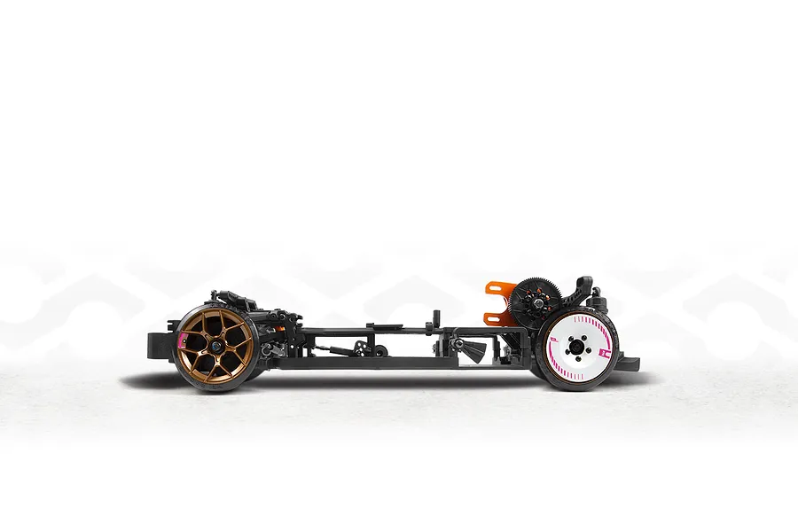 Studio side profile view of the HPI Stage-D10 RC drift car chassis featuring black composite structure, bronze front wheels, white rear wheels, and orange motor mount details.