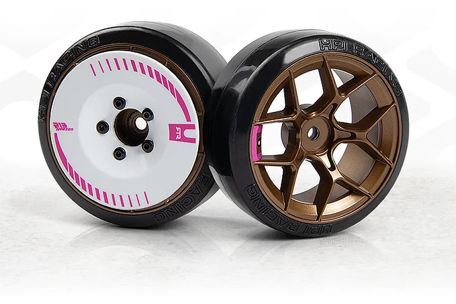 Two RC drift car wheels with slick black rubber tires and bronze rims, one featuring a white aerodynamic disc cover with pink accents.