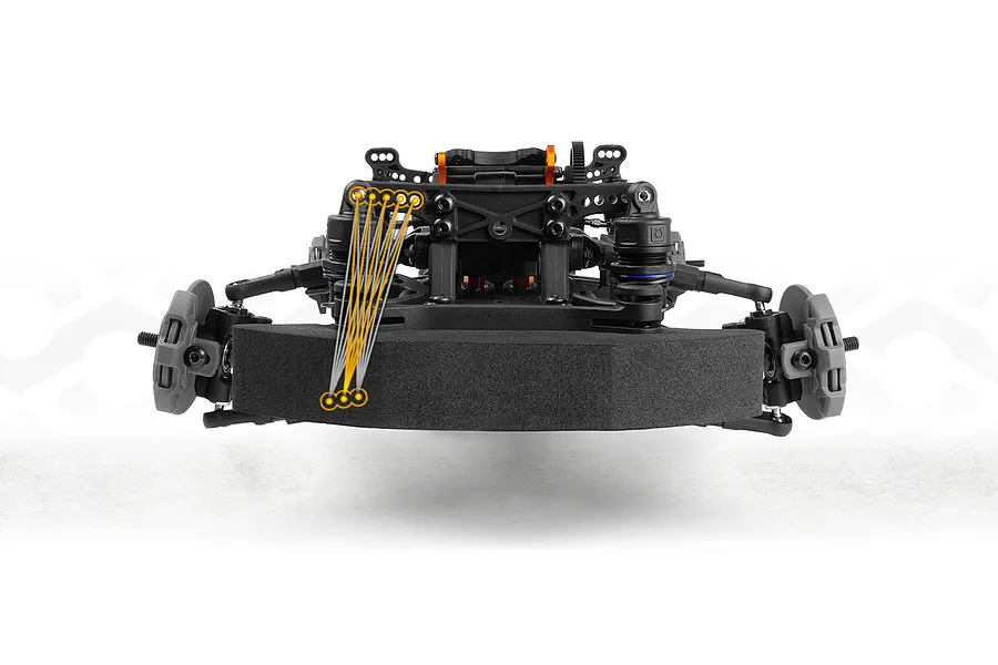 Close-up studio view of an RC drift car front chassis and foam bumper with orange graphic adjustment lines.