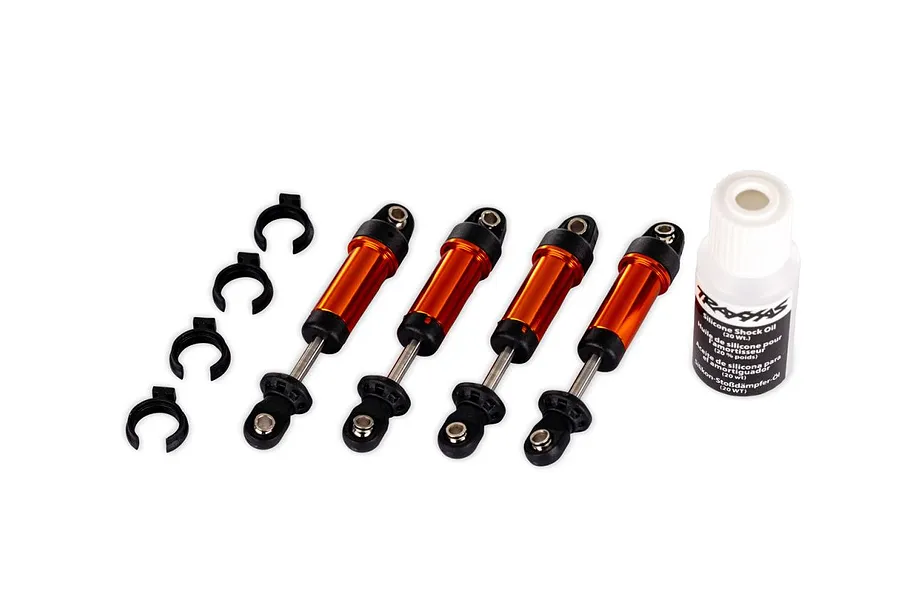 Traxxas aluminium GTM shocks in orange set of four with shock oil and mounting clips on a white background.