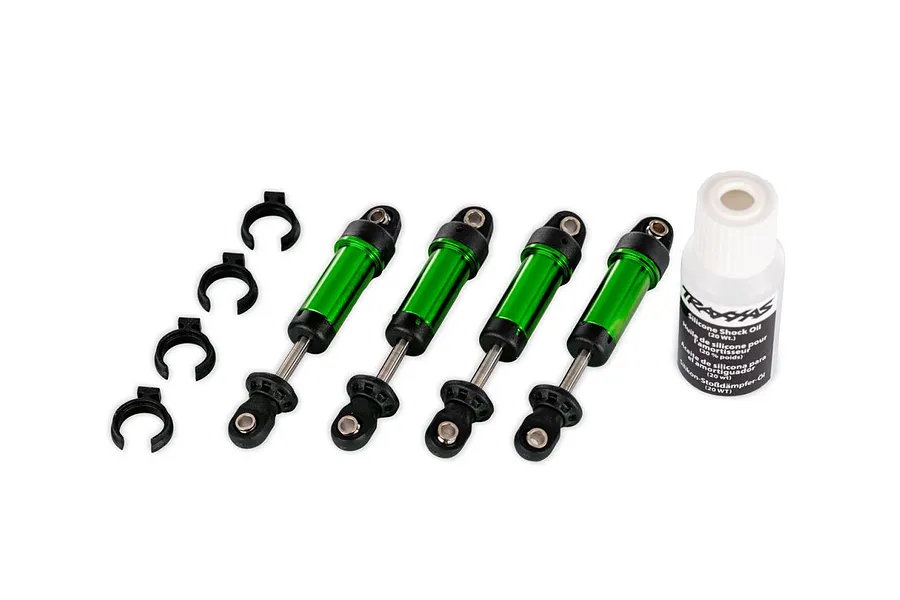 Four green aluminium GTM shock absorbers, four black preload spacers, and a bottle of silicone shock oil.