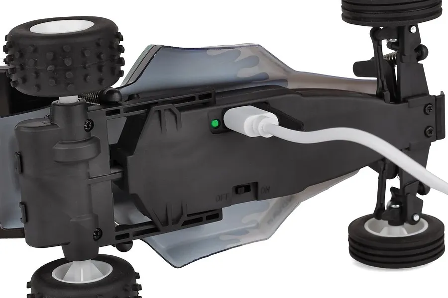Bottom view of the Team Associated RC28 RC buggy showing a USB charging cable plugged into the chassis with a green indicator light.