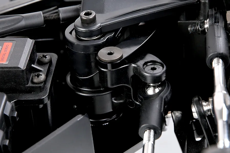 Close-up of black plastic RC car steering assembly, linkage rods, and digital servo from the Rovan Voyager 5 V2.