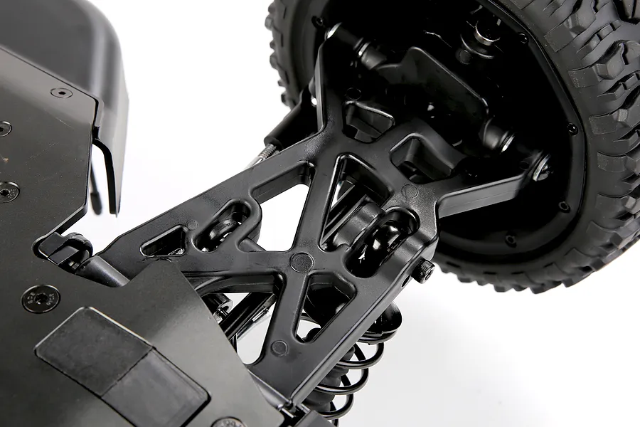 Close-up studio view of the black plastic suspension arm, wheel, and shock absorber on an RC car.