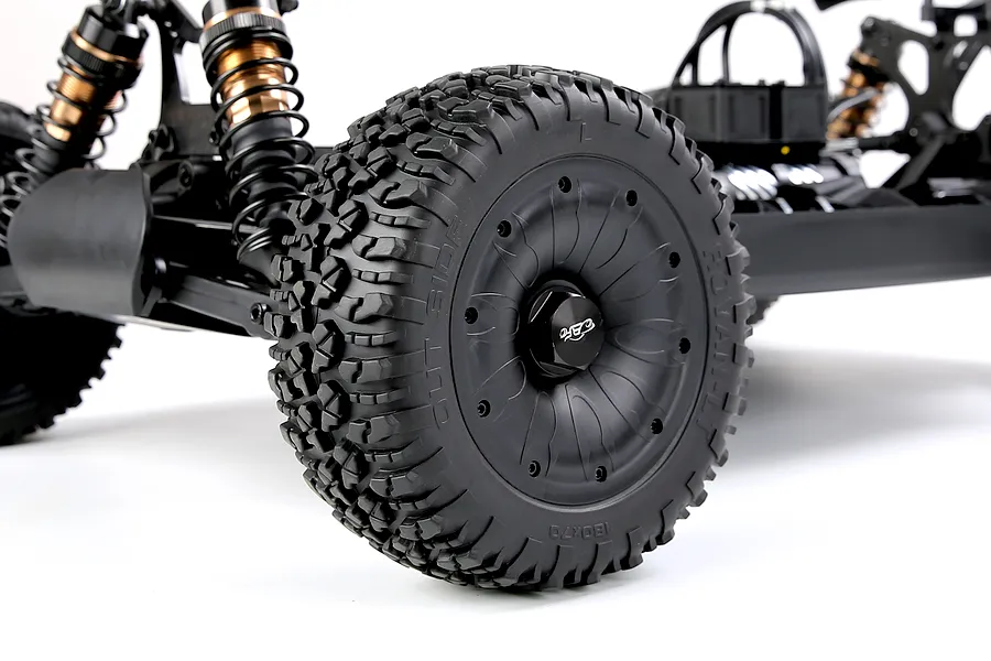 Close up view of the black wheel, chunky tread tyre, and suspension setup on a Rovan 1/5 scale RC buggy.