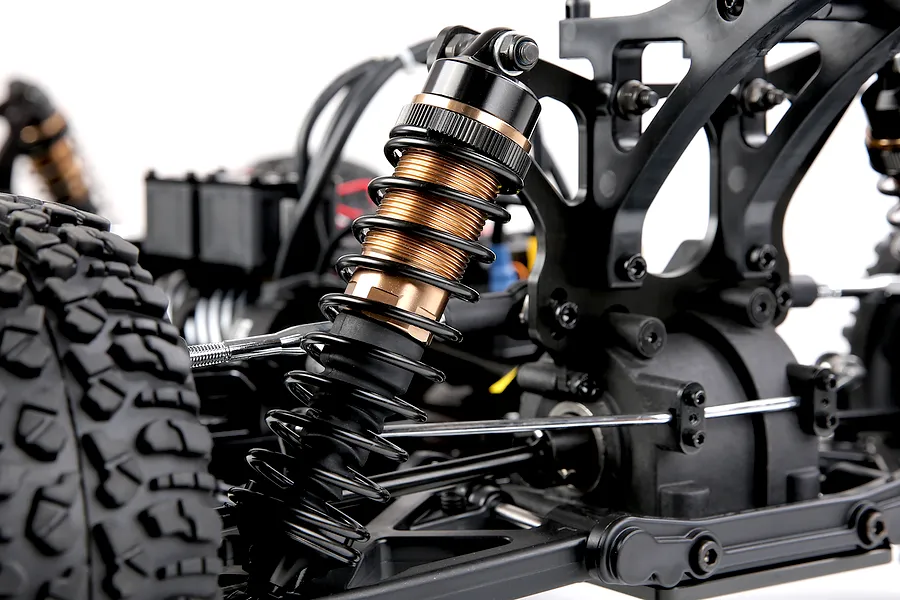 Close up view of the black and bronze colored suspension shock absorber on a Rovan RC buggy chassis.