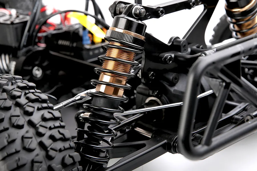 Close-up view of the adjustable metal shock absorber and suspension components on the Rovan ELT320S V2 RC truck.
