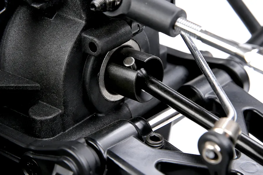 Close-up studio view of the rear differential outdrive, driveshaft, and suspension components on an RC vehicle chassis.