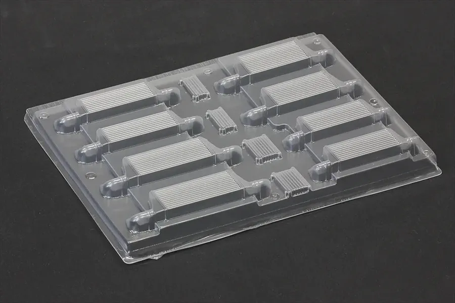 Uncut clear polycarbonate intercooler set sheet for RC body shells on a dark surface.