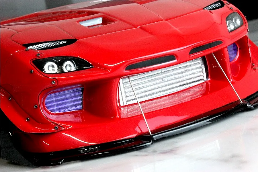 Close-up of a red RC drift car body shell featuring a detailed front-mounted intercooler and splitter.