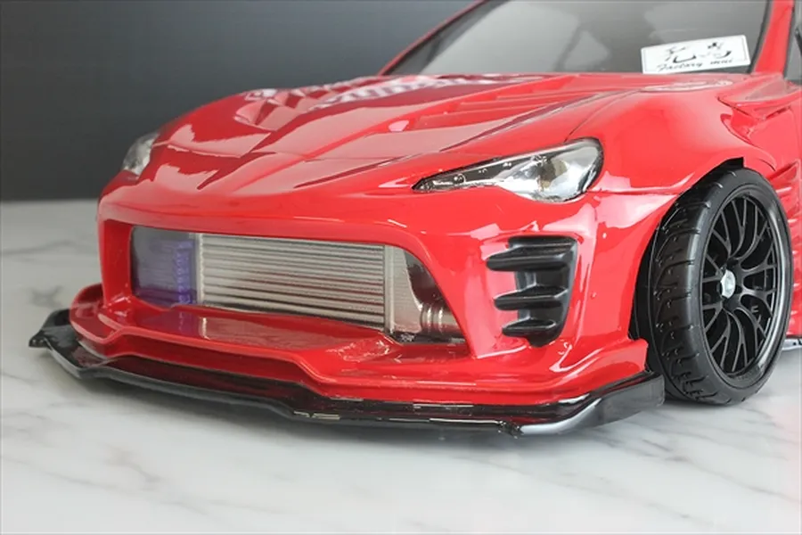 Close-up front view of a red RC drift car body installed with a silver intercooler visible in the front bumper opening.