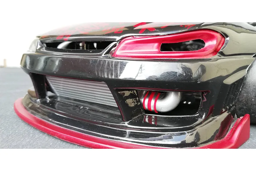 Close-up front view of an RC car body shell installed with a polycarbonate intercooler accessory behind the front bumper grill.