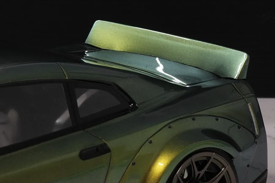 Close-up of a Pandora RC ducktail spoiler installed on the rear of a green and gold metallic RC drift car body.