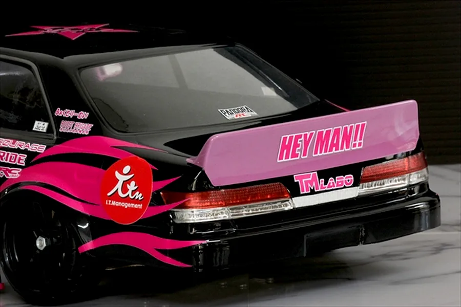 Rear view of a black RC drift car featuring a pink ducktail spoiler with HEY MAN lettering and matching pink side decals.