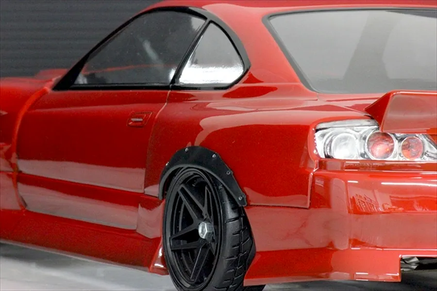 Close-up of a red RC car body showing the rear wheel arch fitted with a black over fender set