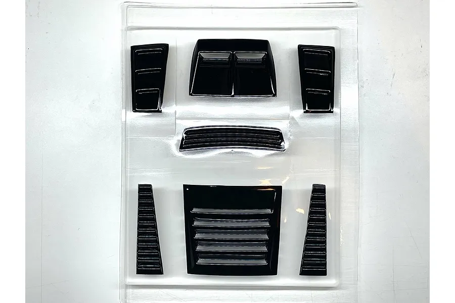 Black plastic RC body shell duct and vent parts set in clear blister packaging on a white surface.
