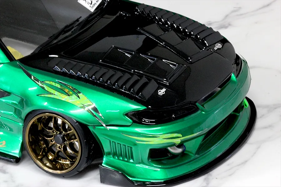Close-up of a custom green and black RC drift car body installed with aerodynamic duct parts and vents on the hood.