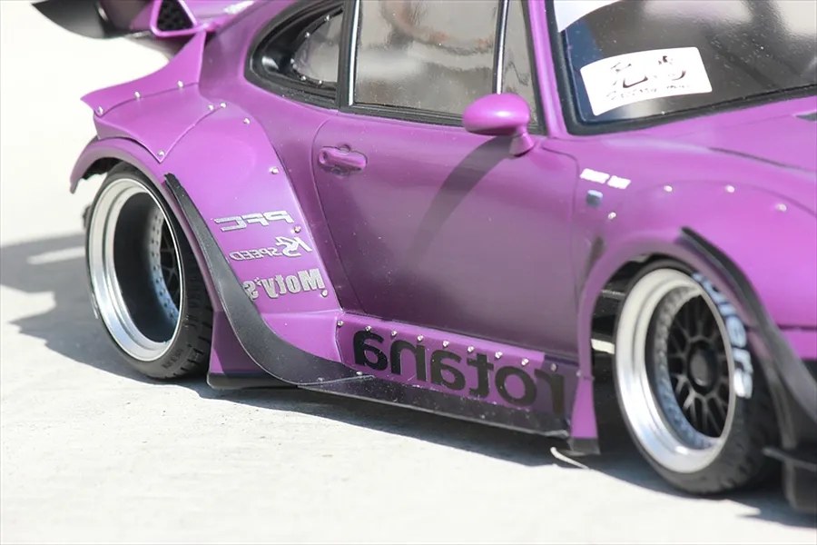 Close-up side profile of a purple RC drift car body installed with wide fenders, deep-dish wheels, and sponsor decals.