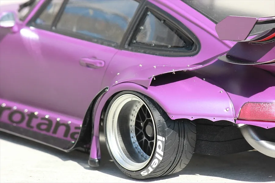 Close-up of a purple RC drift car body shell showing the rear wide fender flare, deep dish wheel, and large wing.