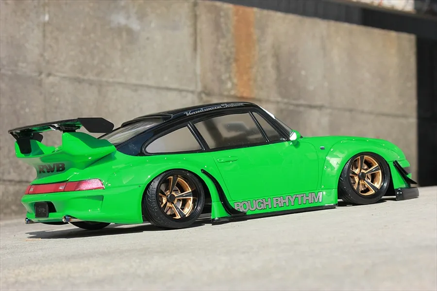 Green RC drift car with wide fenders, black roof, and gold rims parked against a concrete background.