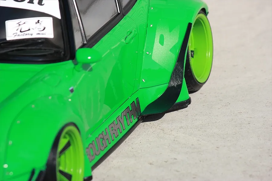 Close-up of a bright green RC car body featuring wide fender flares, black side skirts, and custom wheels.