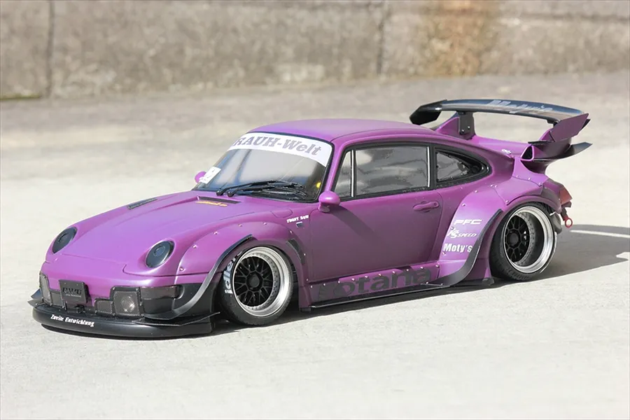 Purple RWB Porsche RC drift car body installed with wide fenders and large rear wing parked outside on concrete.