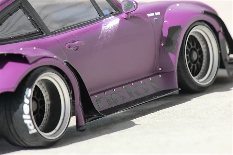 Close-up side profile of a purple RC car body shell featuring wide fenders, custom wheels, and black decals.