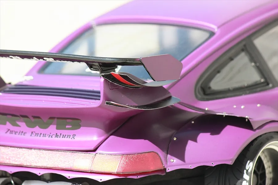 Close-up of the rear section of a purple RC drift car body shell, showing wide fender flares, spoiler wing, and RWB lettering.