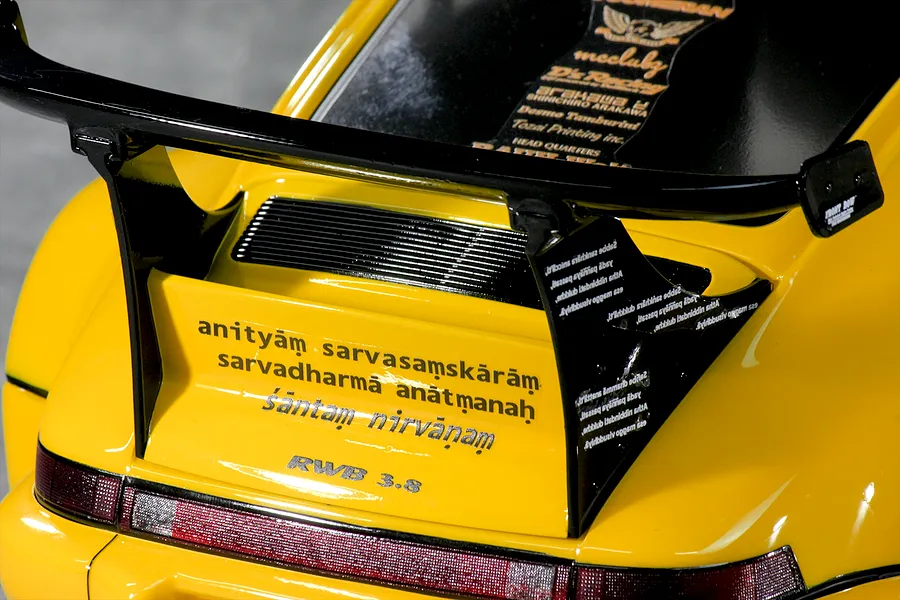 Close-up of the rear decklid and large black wing on a yellow Pandora RC RWB 993 body shell with decals.
