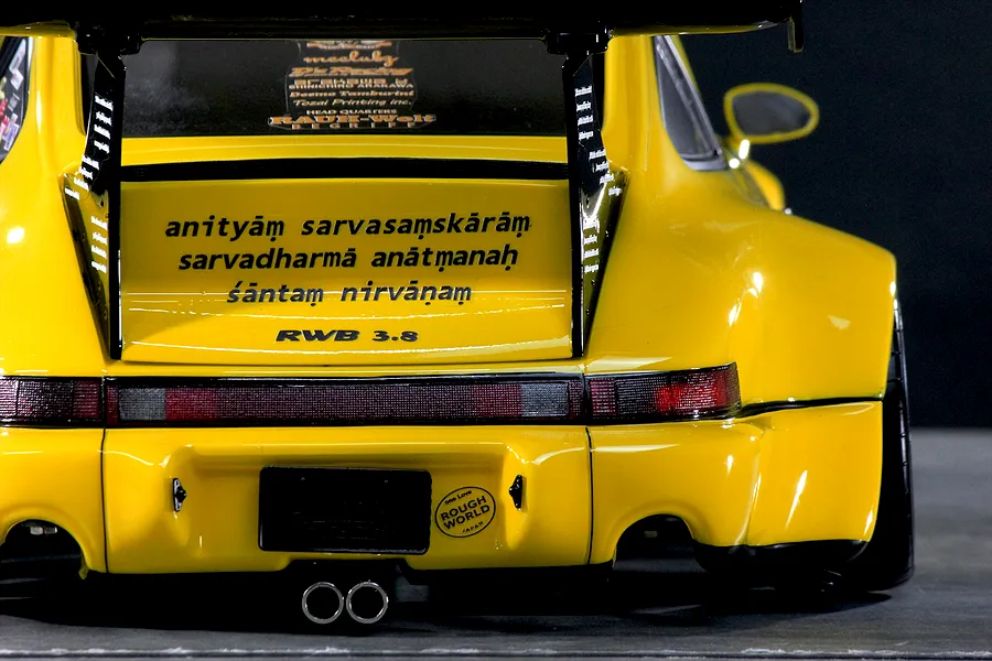 Rear view of a yellow Pandora RC RWB 993 body shell featuring a large rear wing, RWB 3.8 and Sanskrit text decals, and dual exhaust tips.