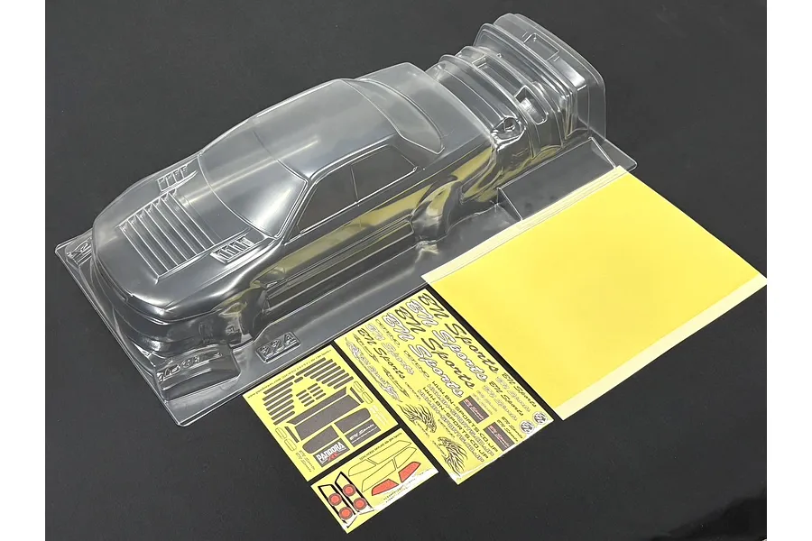 Unpainted clear polycarbonate RC drift car body shell with window masks and decal sheets on a dark background.