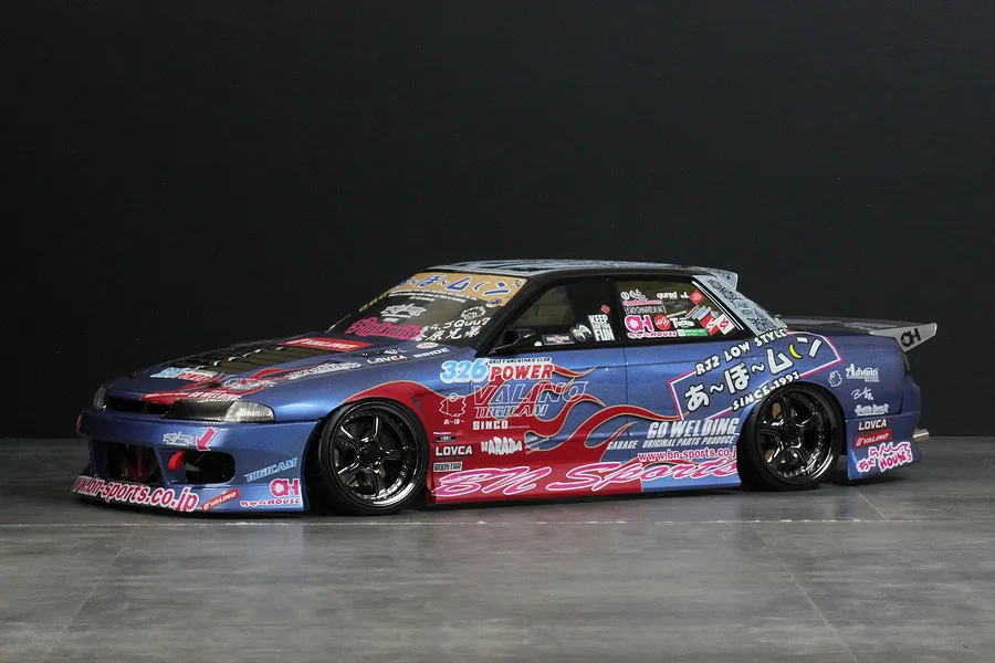 A fully painted and decaled Pandora RC Nissan Skyline R32 4-door drift RC body shell mounted on a chassis against a dark background.