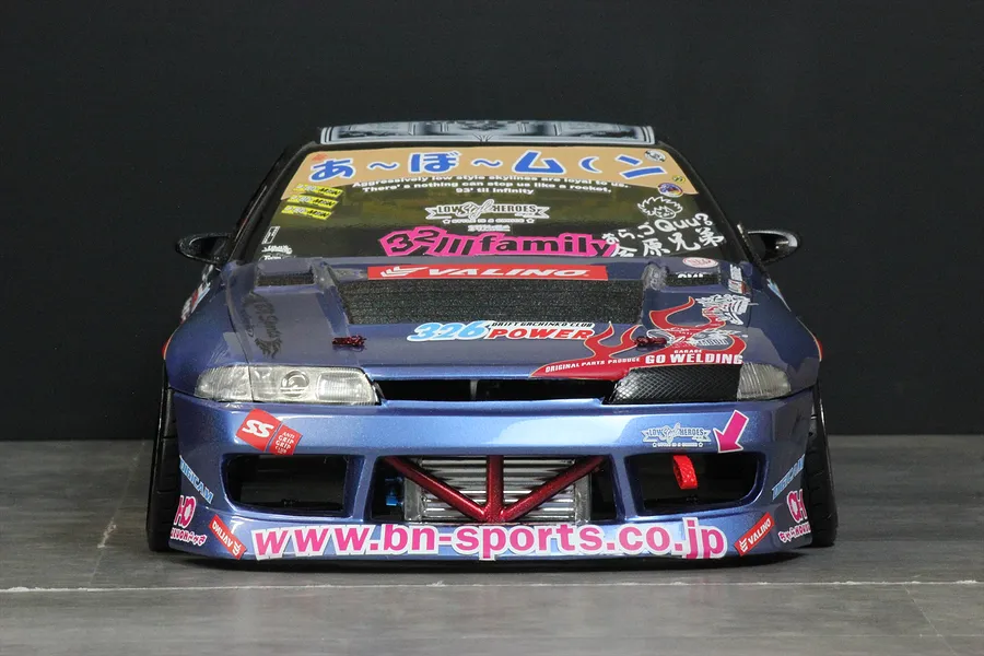 Front view of a blue custom painted RC drift car body shell, featuring decals, an intercooler, and a lowered stance.