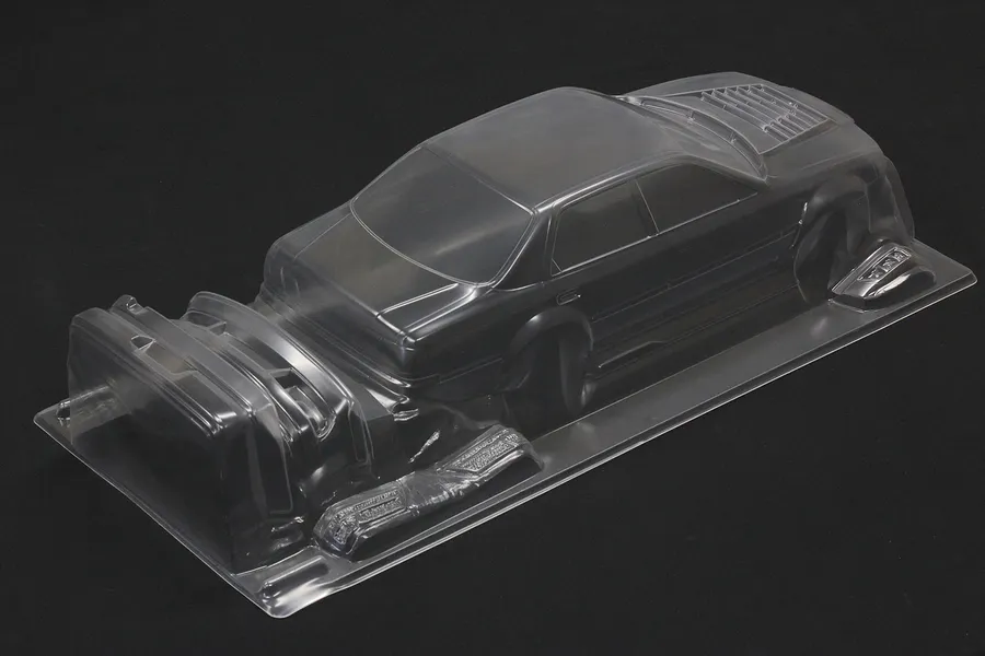 Unpainted clear polycarbonate RC car body shell on a black background, viewed from the rear three-quarters.